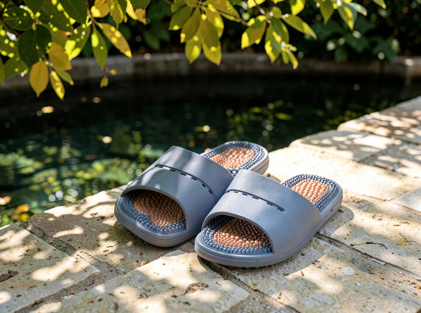 Fecrux slotted band sandals on stone paving beside a pool in dappled afternoon light